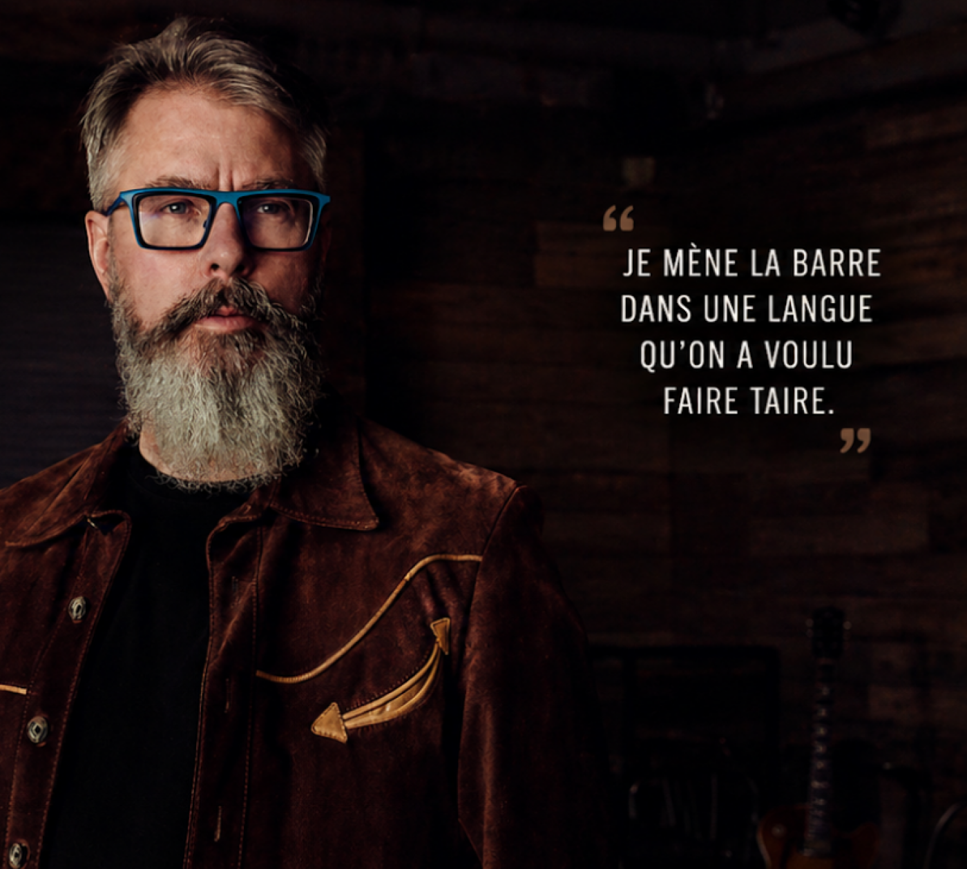 Portrait d'un homme à barbe et lunettes bleues, à côté de la citation : « Je mène la barre dans une langue qu’on a voulu faire taire.