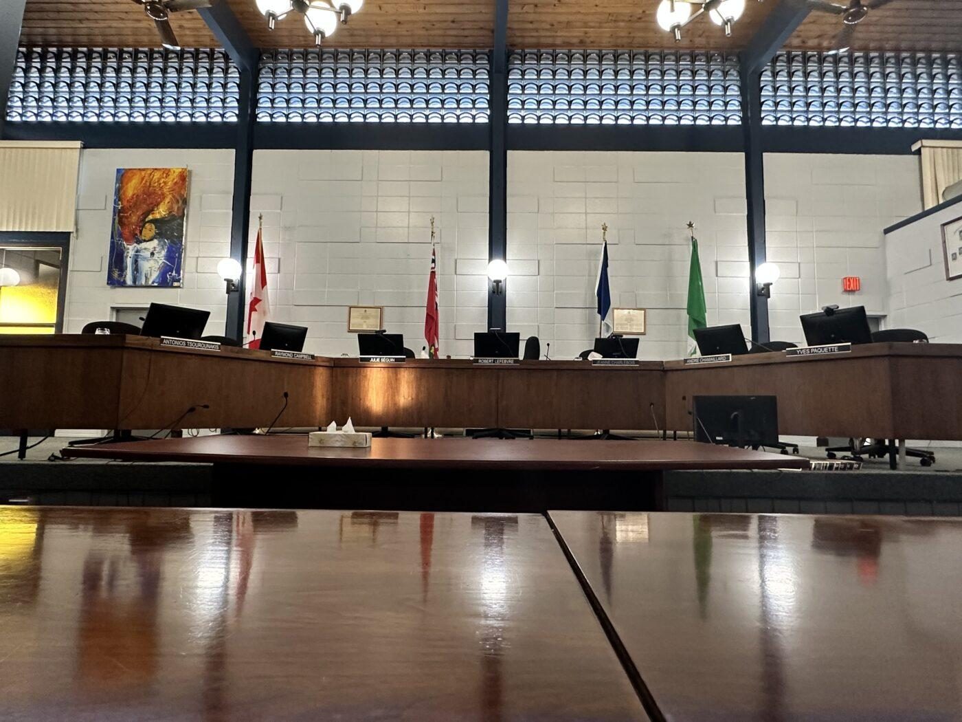 An image of an empty council room, with four flags in the back